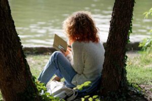 Ragazza legge un libro appoggiata a un albero