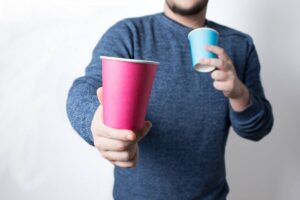 Uomo con due bicchieri di carta in mano