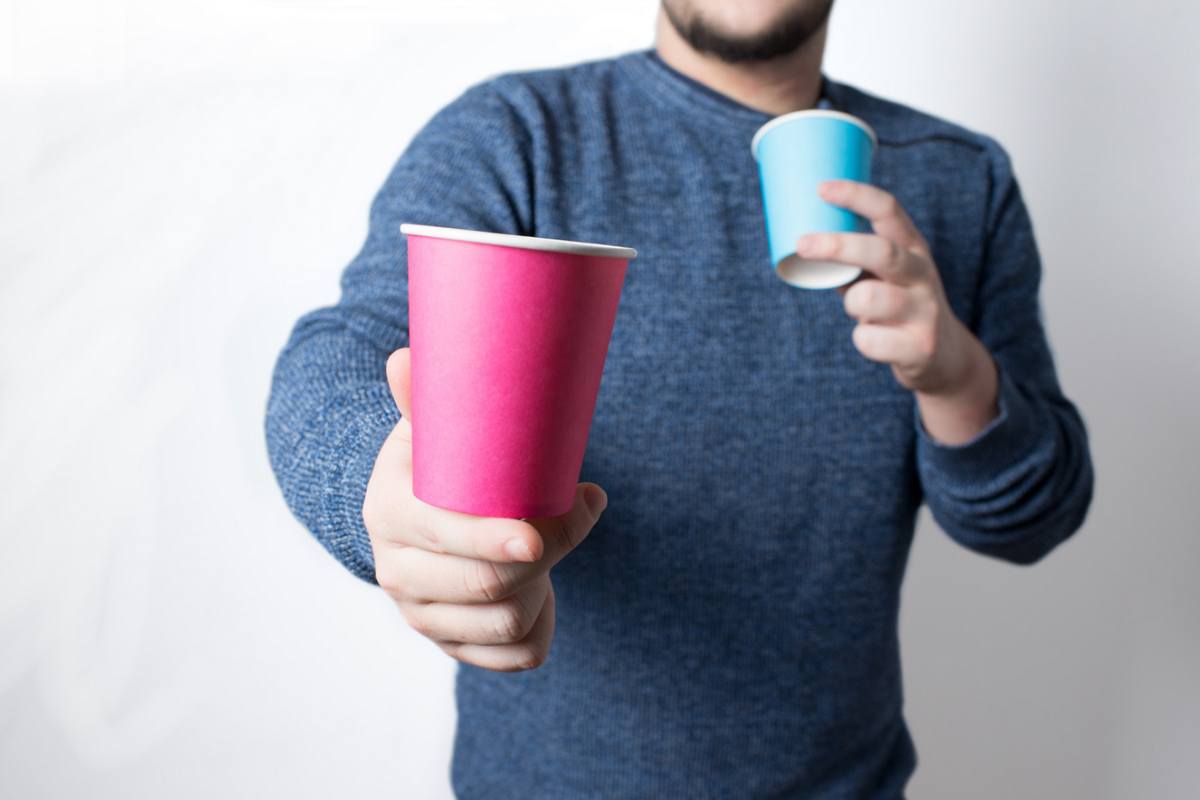 Uomo con due bicchieri di carta in mano