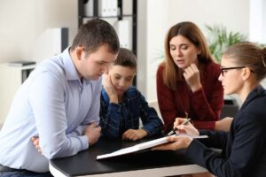 famiglia ad un tavolo con donna che mostra documenti