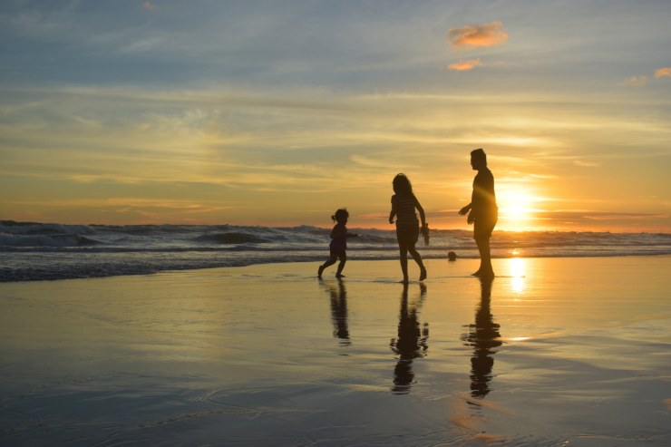 famiglia in riva al mare al tramonto padre madre e figlia