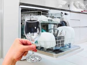 sfondo lavastoviglie aperta e mano che tiene bicchiere
