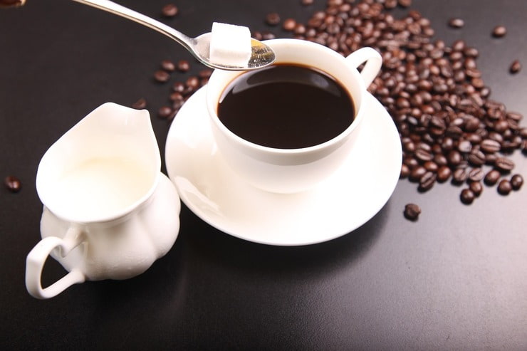 Cucchiaino con una zolletta di zucchero sopra una tazzina da caffè
