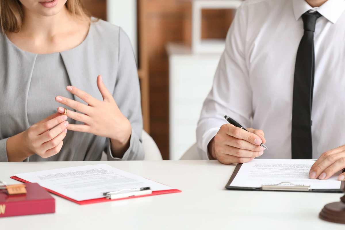 Uomo che firma un foglio e donna che si toglie la fede