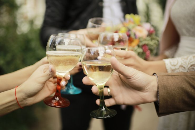 uomini e donne fanno un brindisi con calici di vino