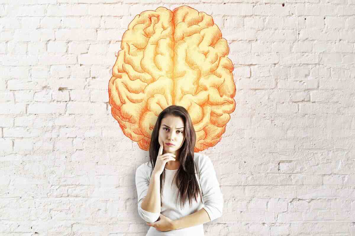 Donna pensierosa riflette, dietro di lei murales di un cervello giallo