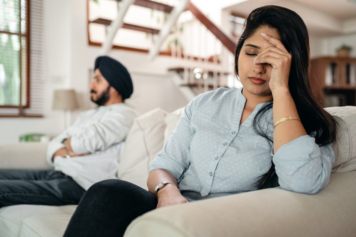 Uomo e donna su divano, che non si parlano e non si guardano