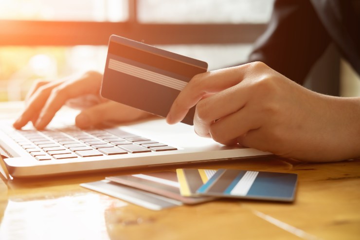 uomo al pc con carta di credito in mano